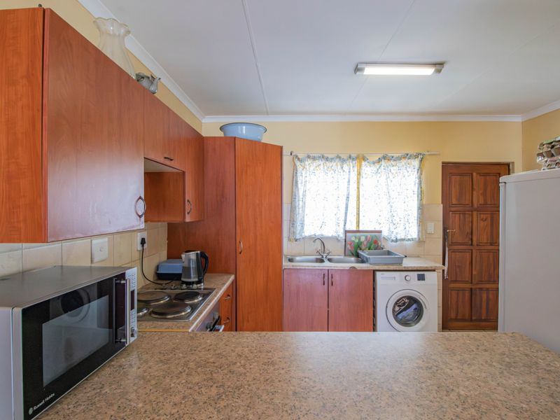 Functional kitchen featuring wood-look cabinetry, laminate countertops, a double basin sink, electric hob, and space for a washing machine.