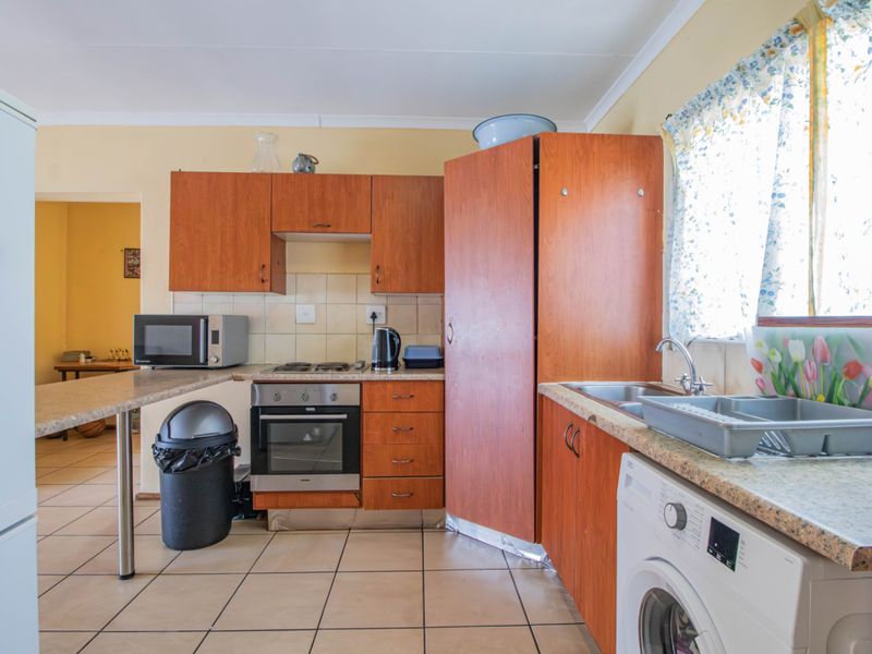 A functional kitchen featuring wood-look laminate cabinetry, tiled flooring, a built-in oven, and a stainless steel sink with a tiled backsplash.