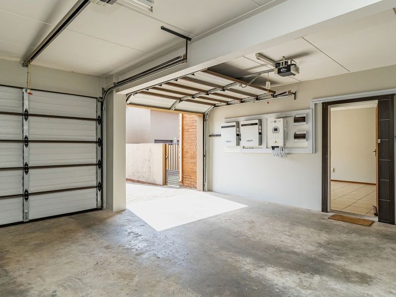 Spacious garage featuring a sectional door, integrated solar power system with inverter and battery storage, and convenient internal access to the home.
