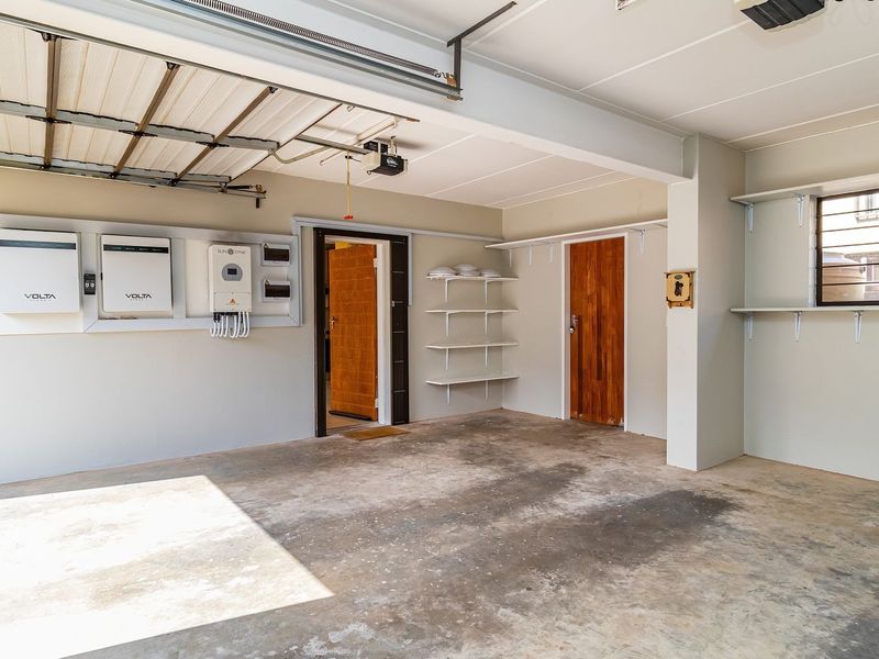 Spacious garage featuring a solar inverter and battery backup system, built-in shelving, and direct internal access.
