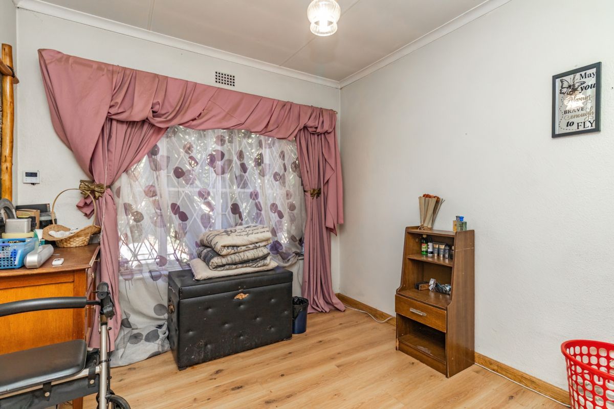 A bedroom featuring light-toned laminate flooring, coved ceilings, and a window with integrated ventilation.