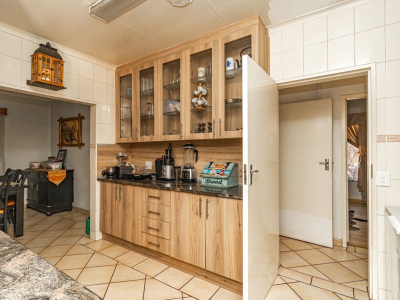 A functional kitchen featuring wood-look cabinetry, granite countertops, and tiled flooring, with direct access to adjacent living areas.