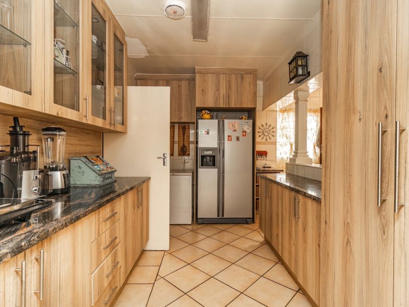 Functional kitchen featuring laminate cabinetry, granite countertops, and tiled flooring, offering ample storage space and a practical layout for daily meal preparation.
