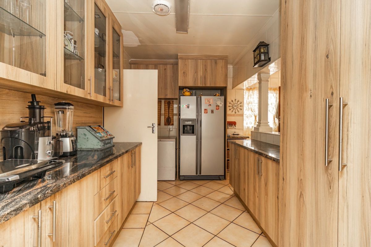 Functional kitchen featuring laminate cabinetry, granite countertops, and tiled flooring, offering ample storage space and a practical layout for daily meal preparation.