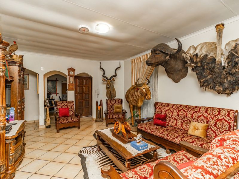 A spacious living room featuring ceramic floor tiles, arched doorways, and a traditional layout, offering a neutral base for potential interior updates.