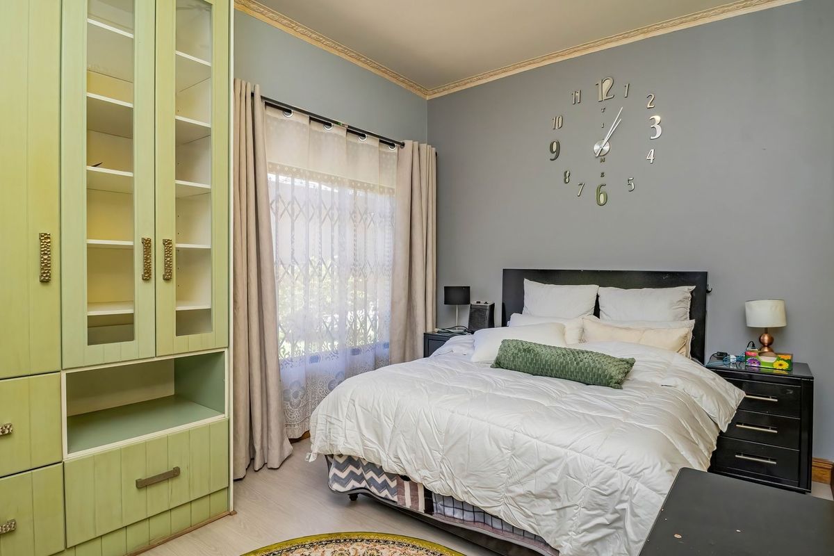 A well-maintained bedroom featuring built-in cabinetry, crown molding, and a security gate on the window, providing a comfortable and functional living space.