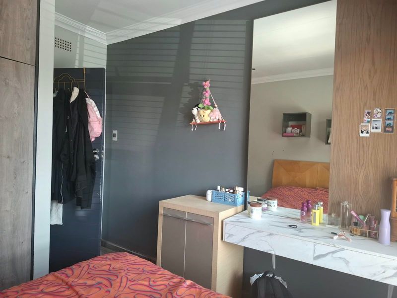 A bedroom featuring a built-in wardrobe, a floating vanity with a marble-effect top, and a large wall-mounted mirror.