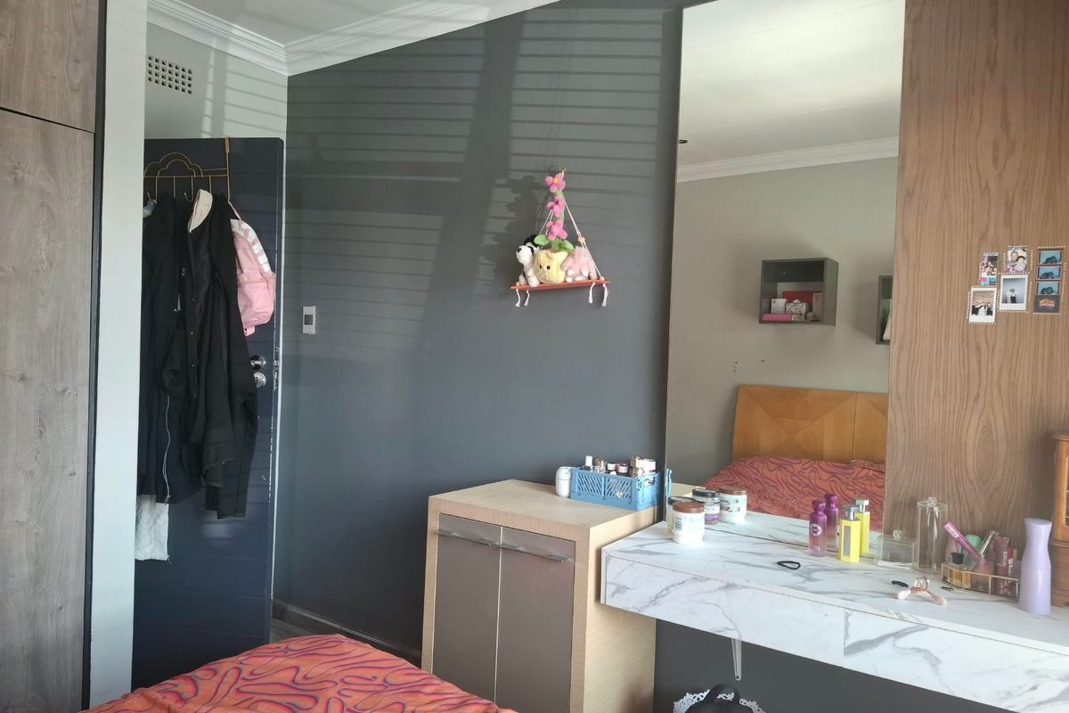 A bedroom featuring a built-in wardrobe, a floating vanity with a marble-effect top, and a large wall-mounted mirror.