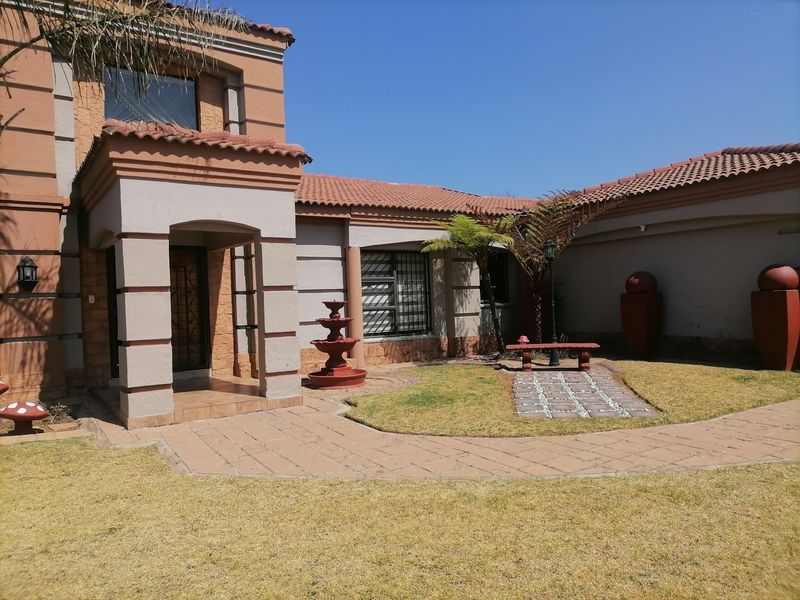 Front exterior view of the house featuring a covered entrance, paved walkway, and landscaped garden area with a water fountain.