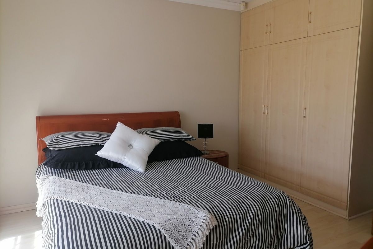 A bedroom featuring light-toned built-in cupboards and laminate flooring, providing functional storage and a neutral base for interior design.