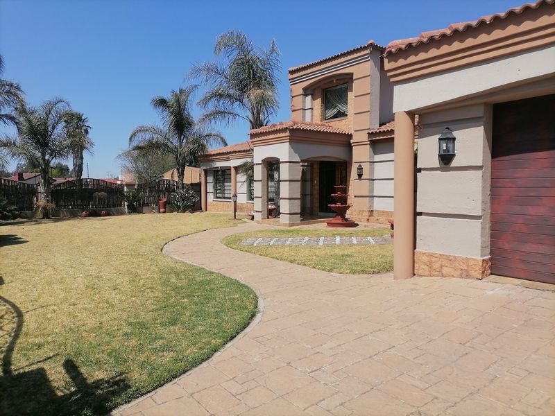 Front elevation of a two-story house featuring a paved driveway, landscaped lawn, and a covered entrance with decorative stone accents.
