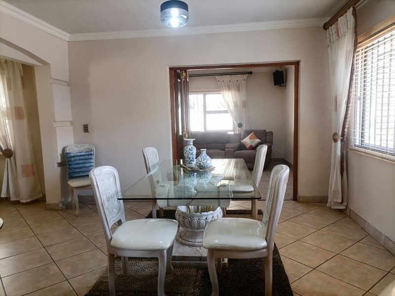 A dining room featuring tiled flooring and double doors leading to an adjacent living area, providing a functional space for family meals.