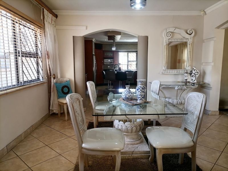 Dining room featuring tiled flooring and an arched entryway leading into a kitchen area with built-in cabinetry.