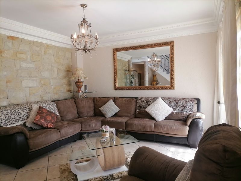 A comfortable living room featuring a textured stone accent wall, elegant crown molding, and classic tiled flooring.