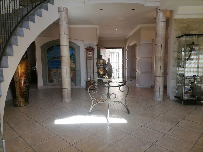 Spacious entrance hall featuring tiled flooring, decorative columns, and a grand staircase, creating an inviting and open transition area for the home.