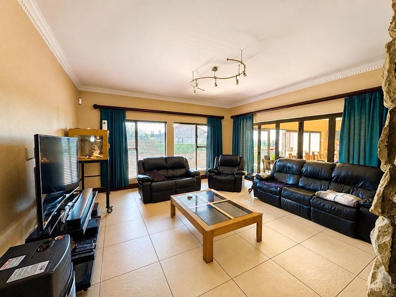 Spacious living room featuring large format floor tiles, crown molding, and expansive sliding glass doors providing natural light and access to the patio.