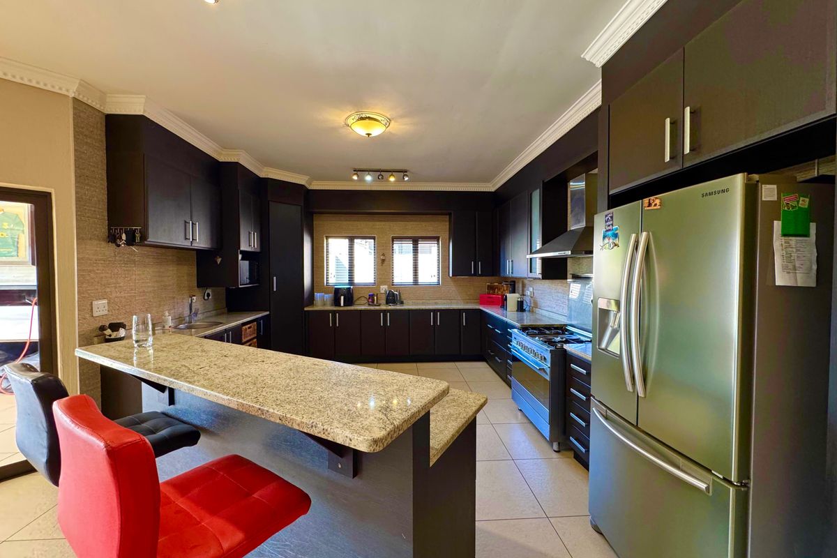 Spacious kitchen featuring dark wood cabinetry, granite countertops, a breakfast bar, and a gas stove with an extractor fan.