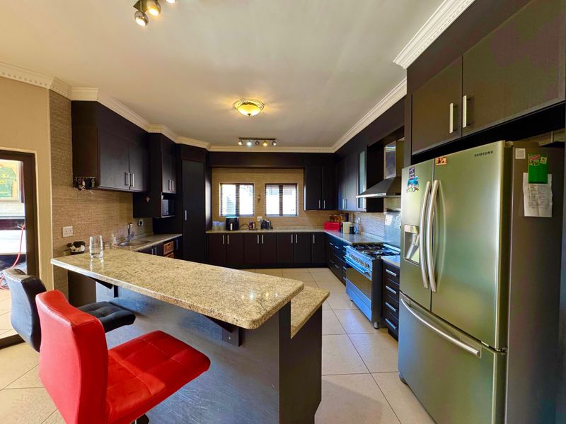 Spacious kitchen featuring dark wood cabinetry, granite countertops, a breakfast bar, and a gas stove with an extractor fan.