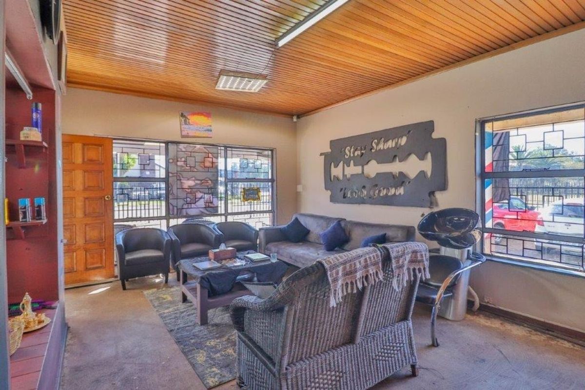 A waiting area or lounge space featuring a timber slat ceiling, security bars on windows, and a functional layout suitable for a business reception.