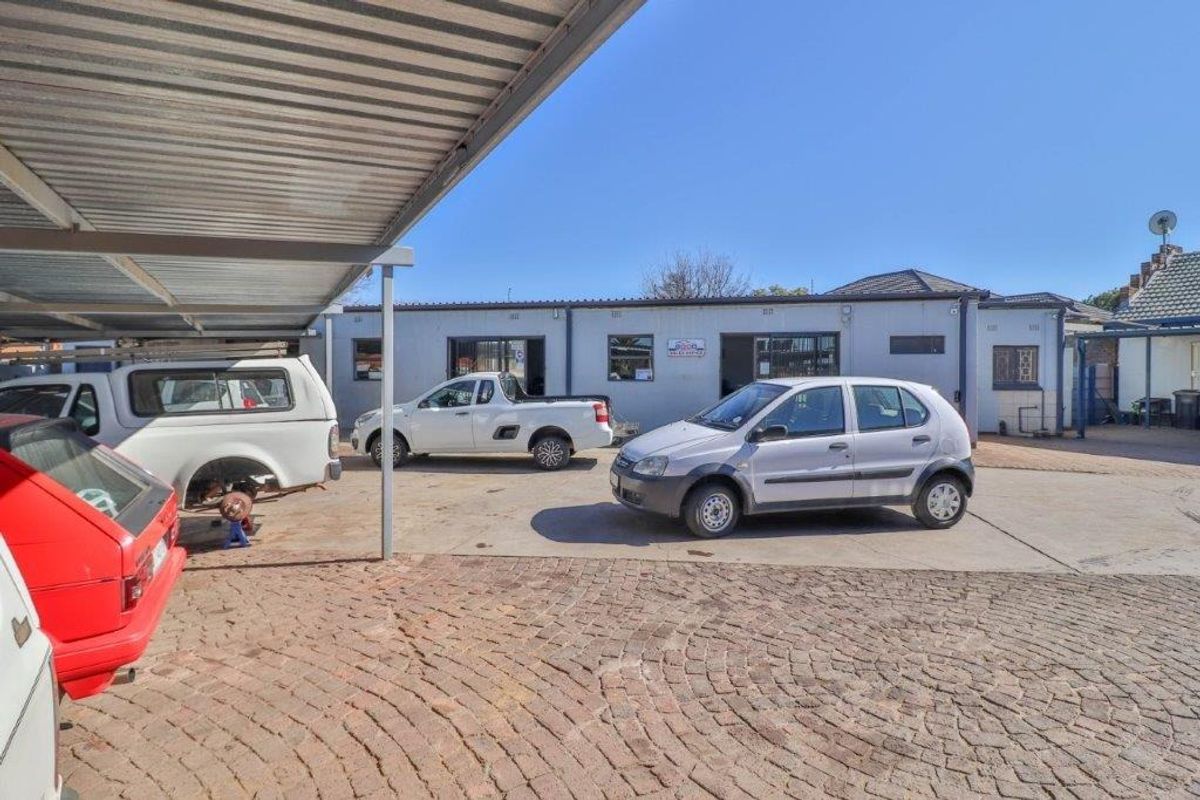 Rear exterior view of the business premises featuring a paved yard area and a covered carport structure.