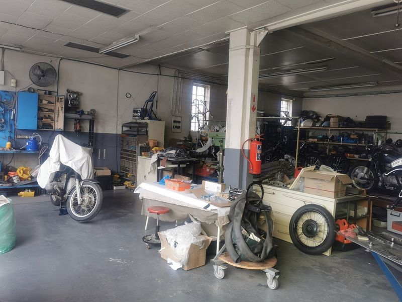 Spacious industrial garage area featuring concrete flooring, built-in storage shelving, and overhead fluorescent lighting, suitable for workshop or storage use.
