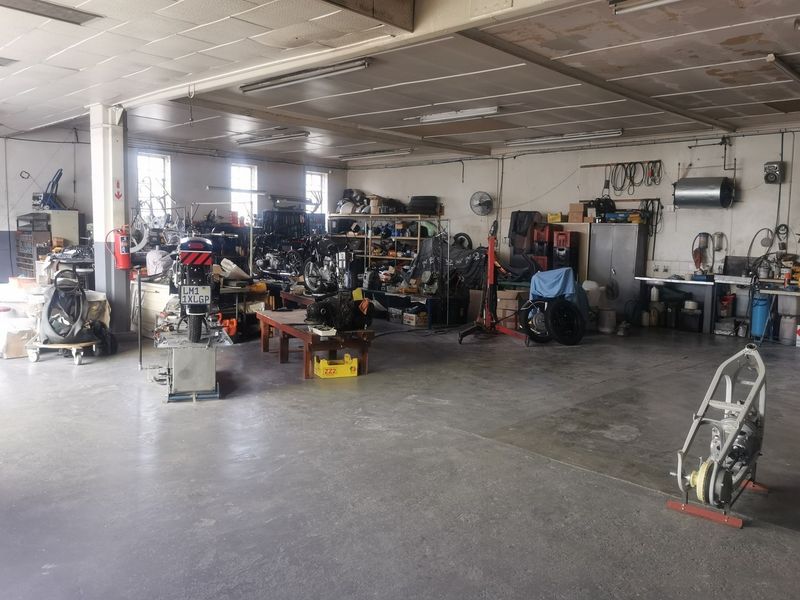 Spacious industrial garage or workshop area featuring concrete flooring, fluorescent lighting, and functional utility space suitable for automotive or storage use.