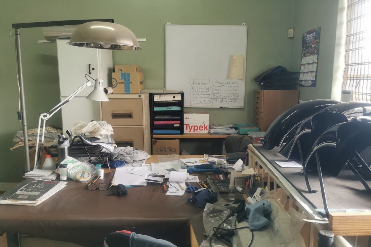 A functional industrial office space featuring a whiteboard and built-in storage, suitable for administrative or workshop management tasks.