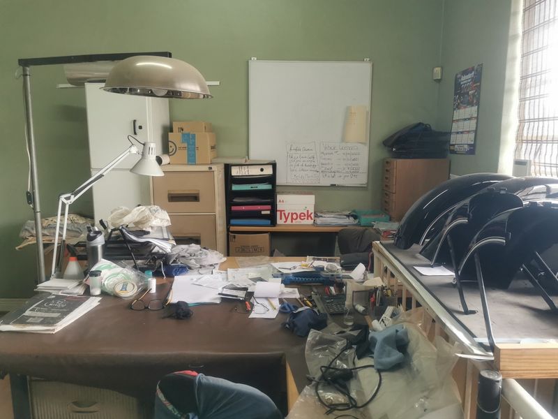 A functional industrial office space featuring a whiteboard and built-in storage, suitable for administrative or workshop management tasks.