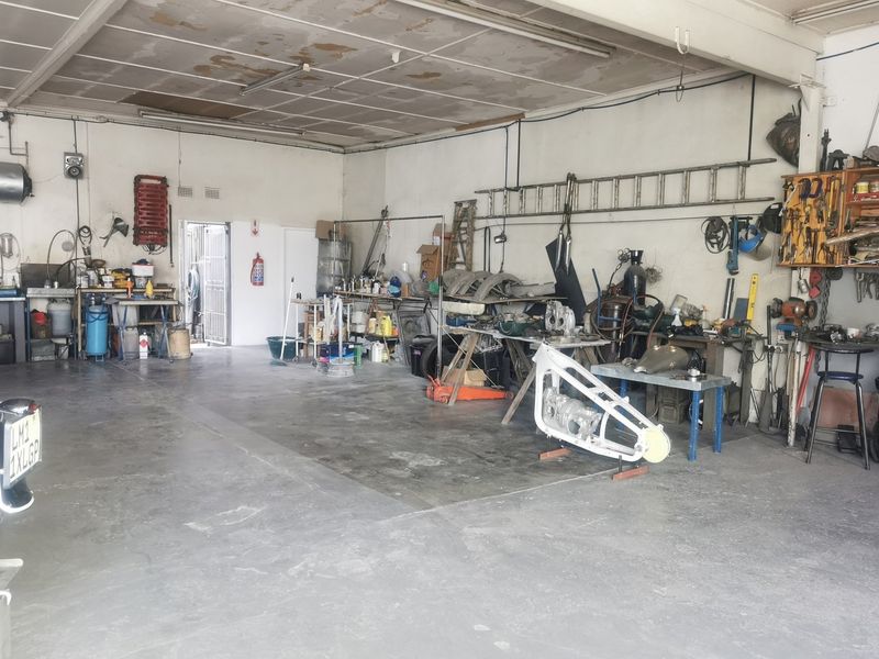 Spacious industrial garage featuring concrete flooring, exposed ceiling panels, and a secure entrance, suitable for workshop or storage use.