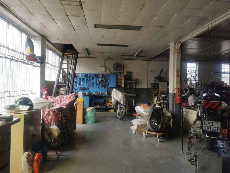 Spacious industrial garage or workshop area featuring concrete flooring, high ceilings with integrated lighting, and functional wall-mounted storage infrastructure.