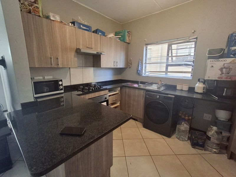 Functional kitchen featuring granite countertops, built-in cabinetry, gas hob, under-counter oven, and tiled flooring with space for integrated appliances.