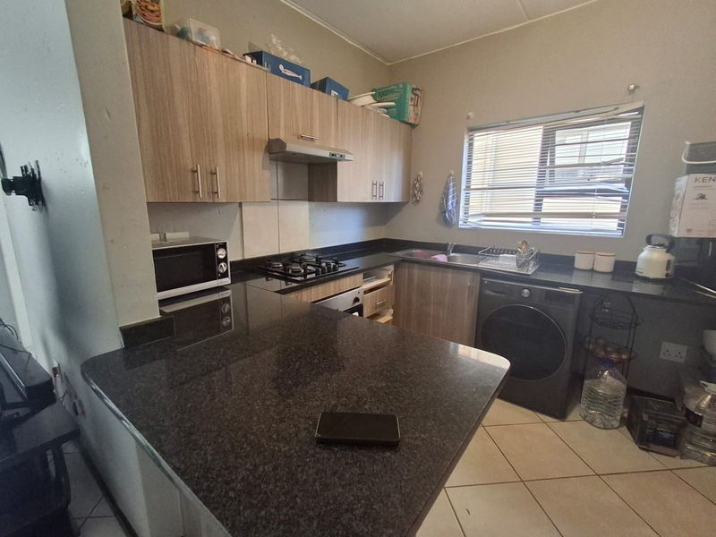 Functional kitchen featuring granite countertops, built-in cabinetry, gas hob, extractor fan, and under-counter oven with tiled flooring.