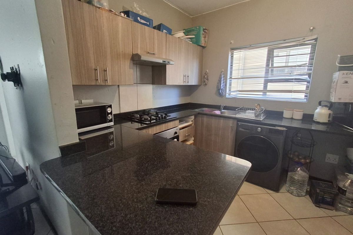 Functional kitchen featuring granite countertops, built-in cabinetry, gas hob, extractor fan, and under-counter oven with tiled flooring.