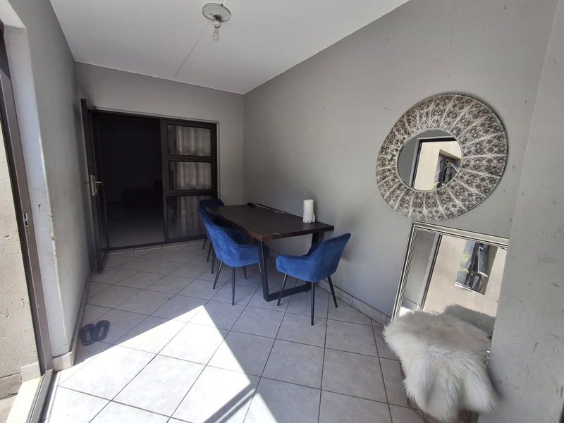 A covered patio area featuring tiled flooring and a sliding glass door, providing a functional outdoor space for dining or relaxation.