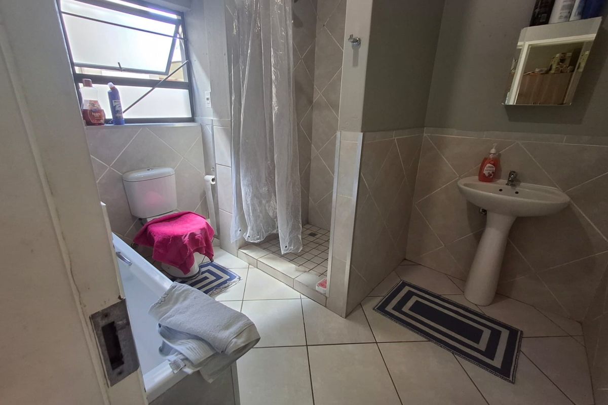 A functional bathroom featuring a pedestal basin, a separate shower cubicle, a bathtub, and a toilet with tiled finishes.