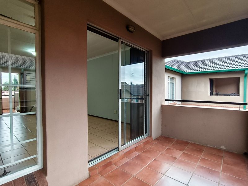 A covered balcony featuring tiled flooring, a metal balustrade, and sliding glass door access to the interior living space.