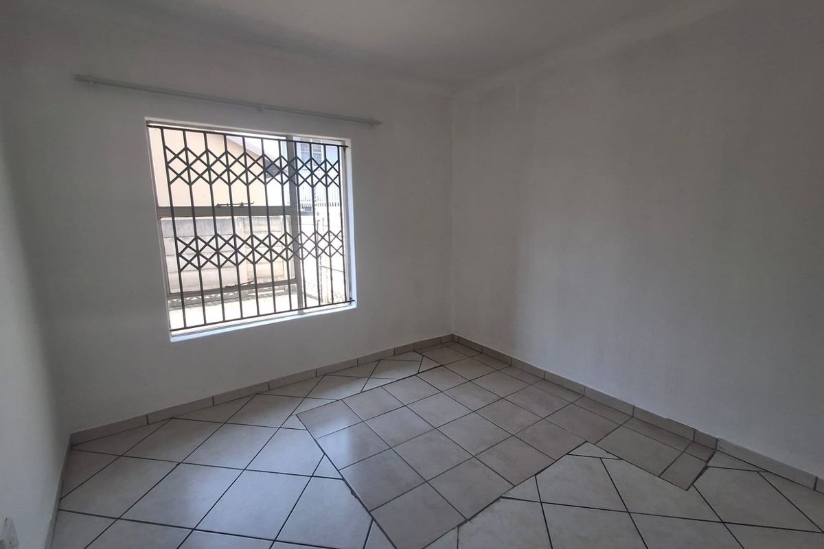 An empty bedroom featuring tiled flooring and a window fitted with a security gate, providing a blank canvas for personalization.