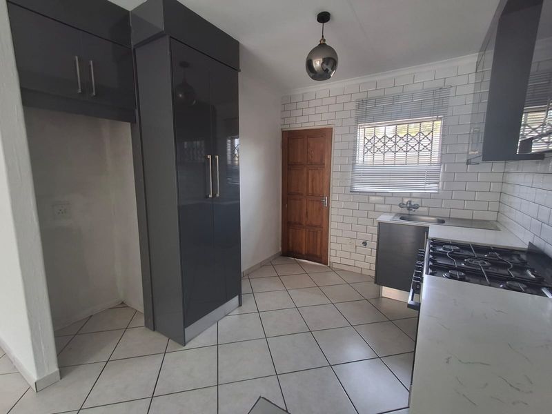 Modern kitchen featuring dark grey cabinetry, white subway tile backsplash, gas hob, and tiled flooring with a functional layout.