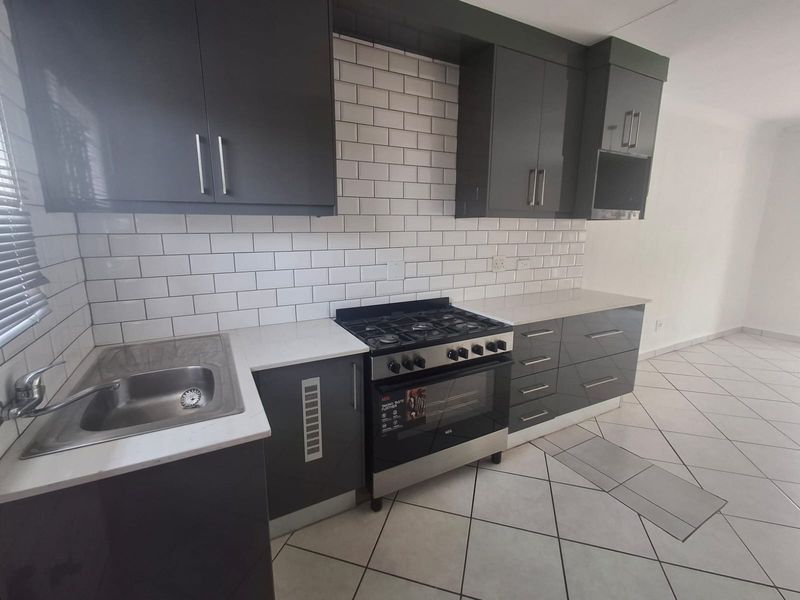 Modern kitchen featuring dark grey cabinetry, white quartz countertops, subway tile backsplash, and a stainless steel gas stove with oven.
