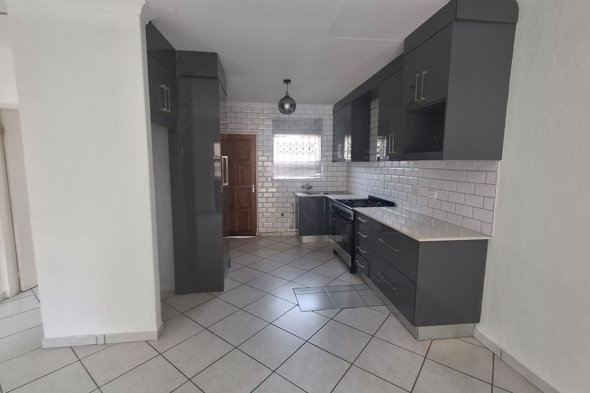 Modern kitchen featuring dark grey cabinetry, white subway tile backsplash, gas stove, and neutral ceramic floor tiles.