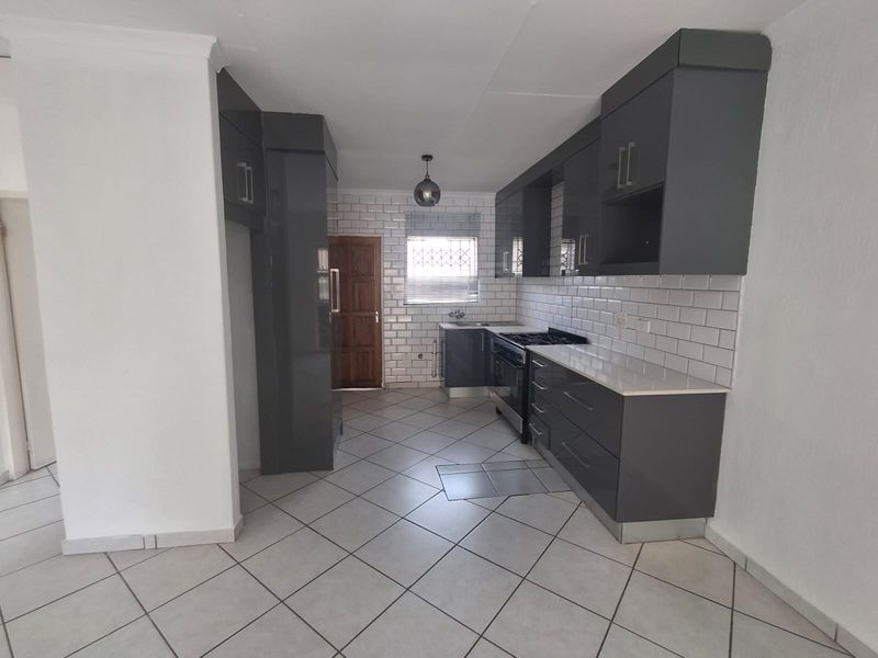 Modern kitchen featuring dark grey cabinetry, white subway tile backsplash, gas stove, and neutral ceramic floor tiles.