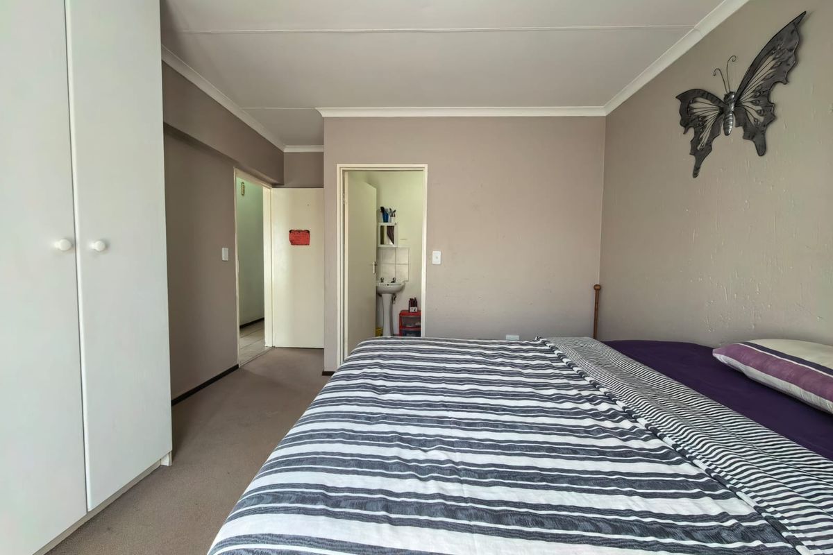 A bedroom featuring built-in wardrobes, carpeted flooring, and direct access to an en-suite bathroom.