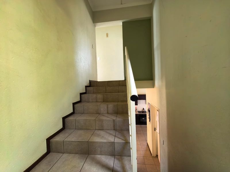 A functional staircase area featuring tiled steps and a metal handrail, connecting different levels of the townhouse.