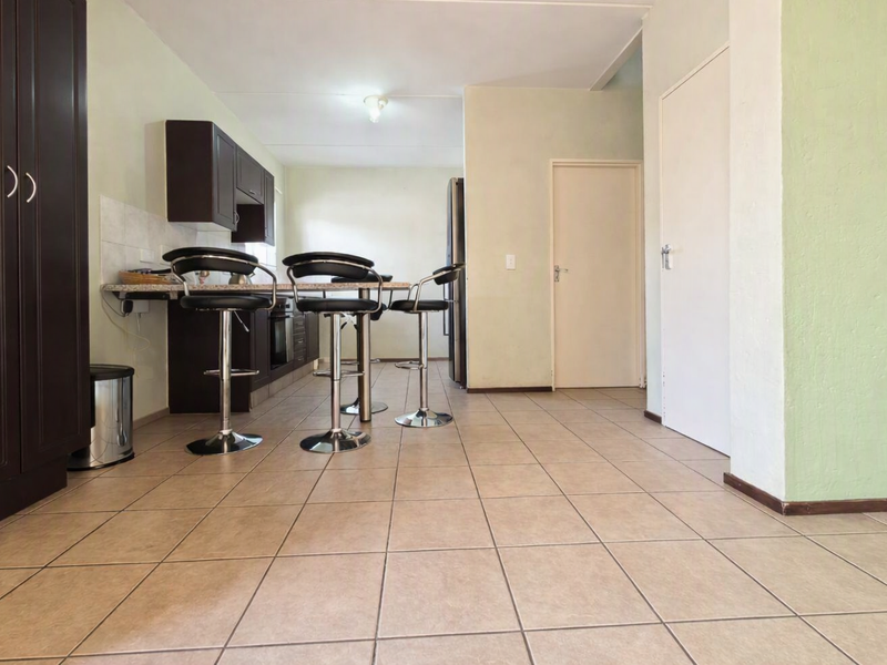 A functional kitchen area featuring dark cabinetry, a breakfast bar, and tiled flooring, offering a practical layout for daily use.