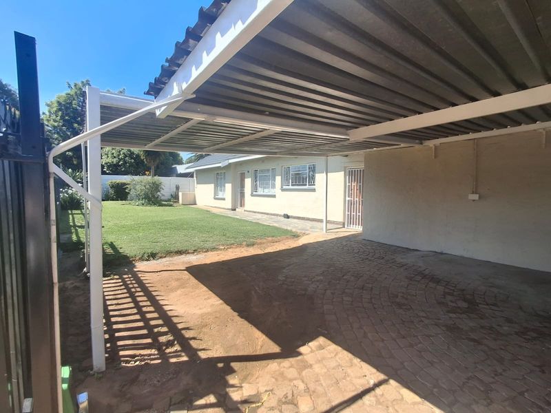 A functional carport area with paved driveway, security features, and direct access to the main house structure.