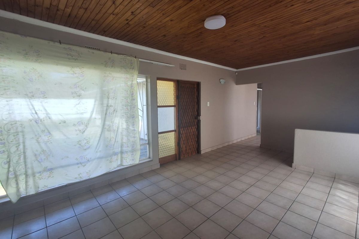 An empty living area featuring ceramic floor tiles and a timber tongue and groove ceiling, providing a blank canvas for renovation.