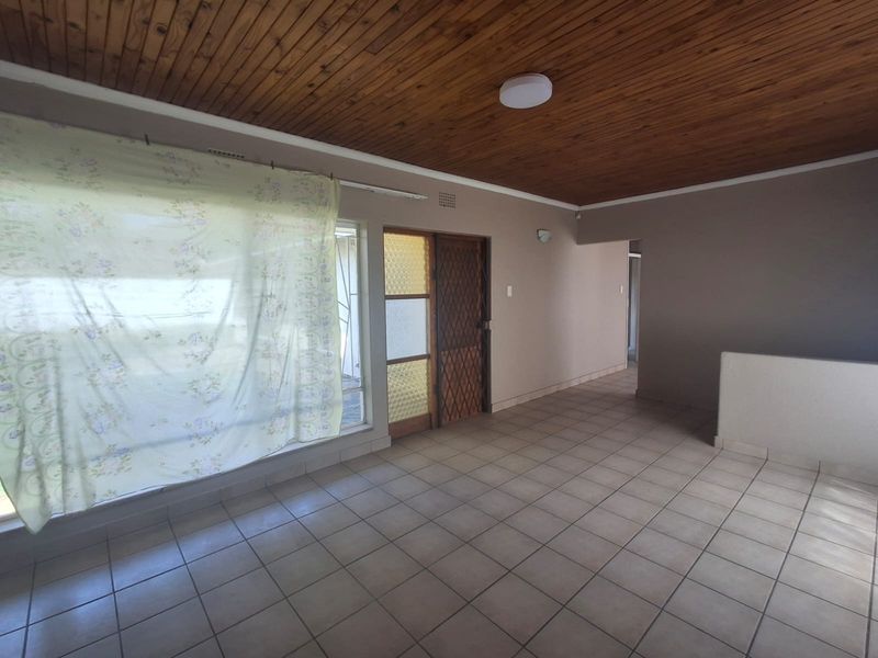 An empty living area featuring ceramic floor tiles and a timber tongue and groove ceiling, providing a blank canvas for renovation.
