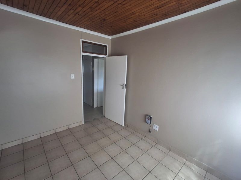 An empty bedroom featuring tiled flooring and a wooden tongue and groove ceiling, providing a neutral canvas for interior design.