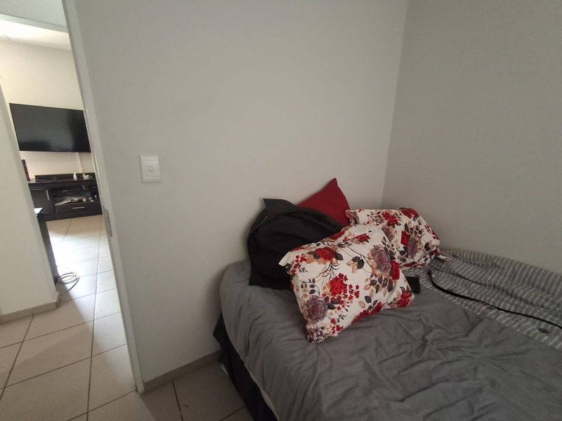 A bedroom featuring tiled flooring and a view into the adjacent living area.