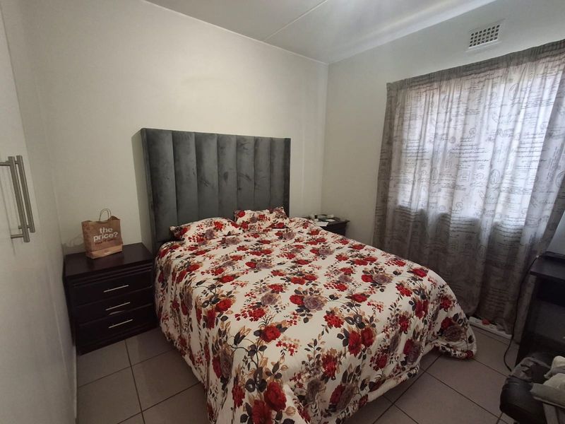 A functional bedroom featuring tiled flooring, a built-in cupboard, and a ceiling ventilation unit.